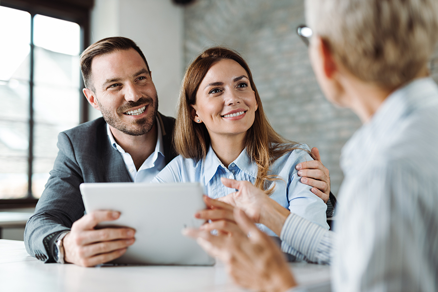 Young happy couple talking to a mortgage agent about how to pay down their debt faster by doing a debt consolidation Young happy couple talking to a mortgage agent about how to pay down their debt faster by doing a debt consolidation.